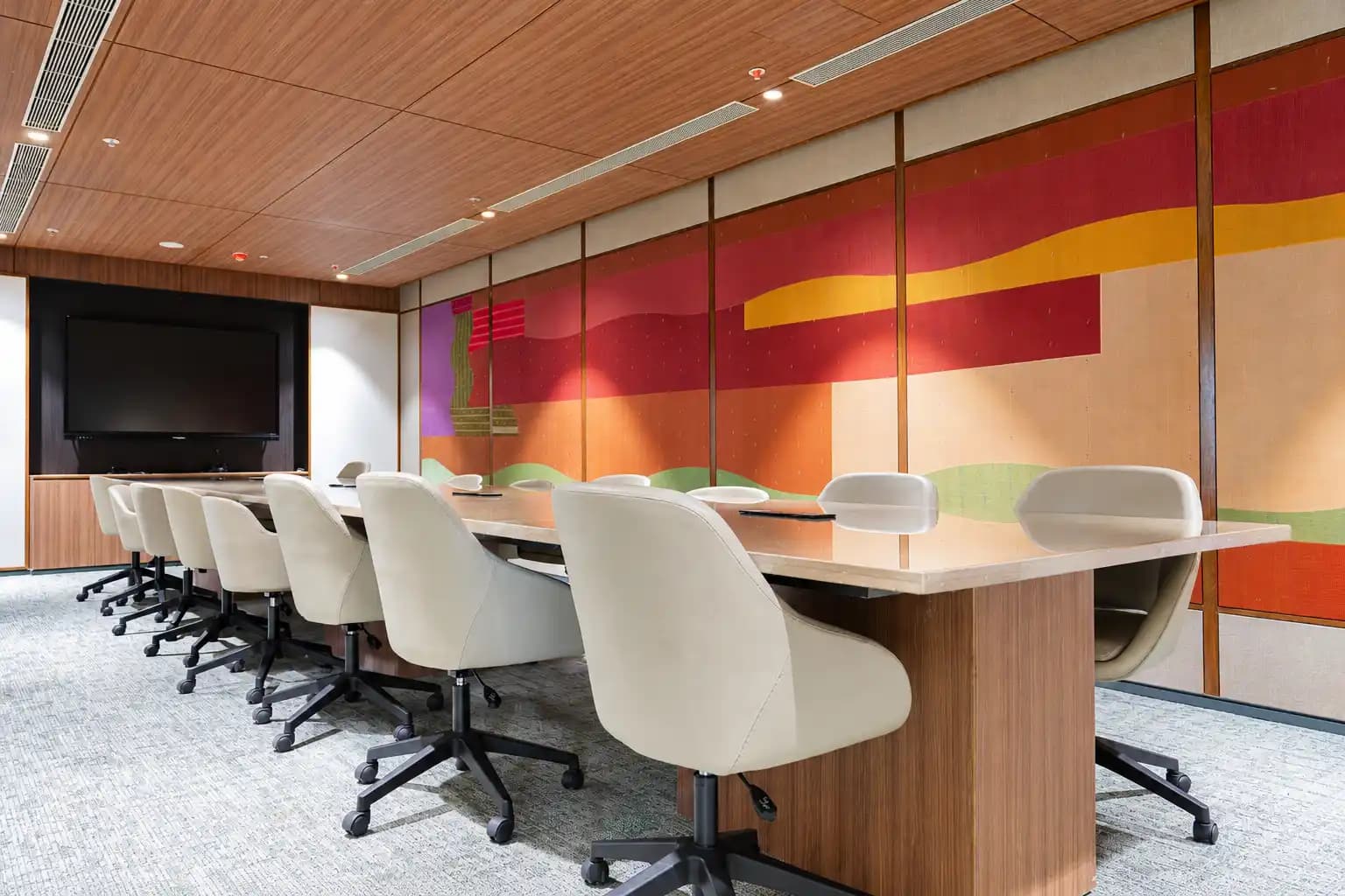 A meeting room at ClayWorks Senate with a timber ceiling, a woven textile mural and a wall-mounted display