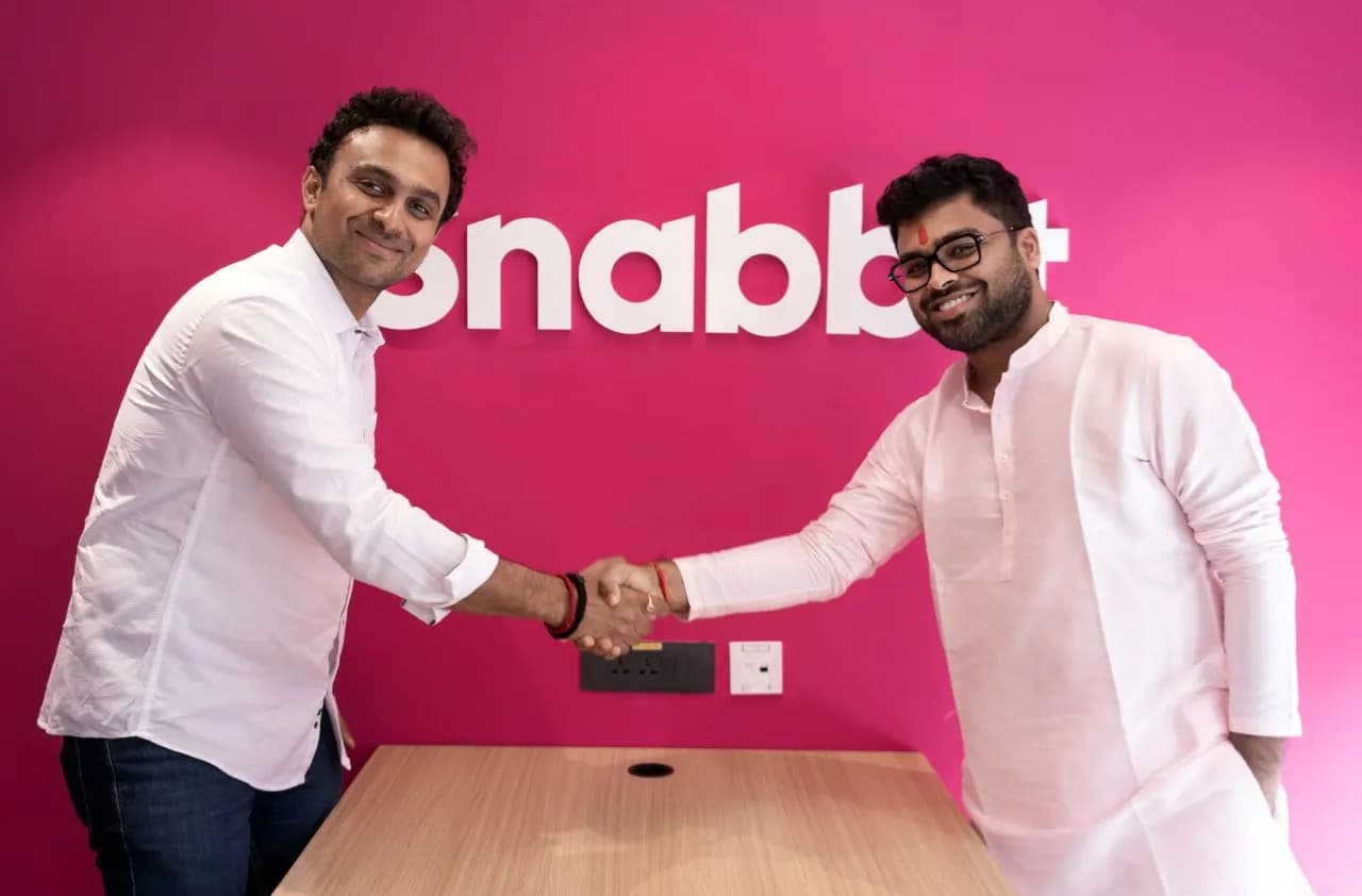 A handshake in front of the Snabbit logo wall at its ClayWorks 5B headquarters